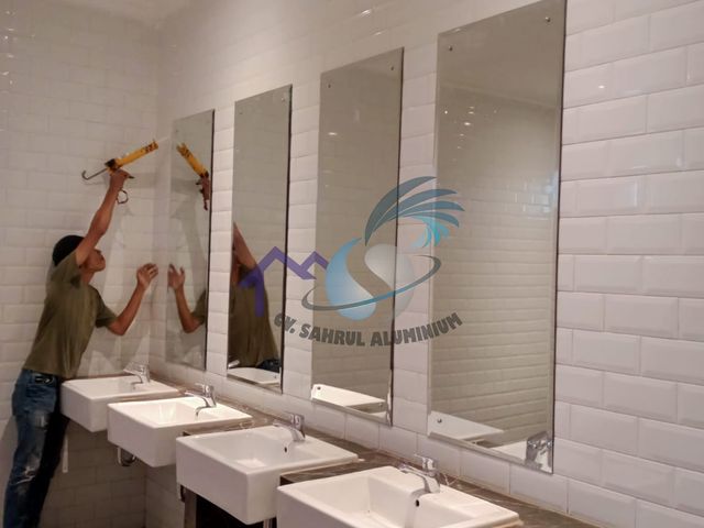 Pemasangan kaca cermin panjang pada area wastafel toilet oleh CV. Sahrul Aluminium